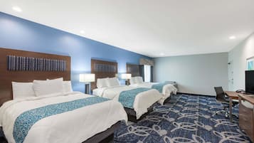 A hotel room with three beds, a desk, and a chair.