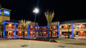 A multi-story hotel with a central courtyard, featuring palm trees and a 'No Parking' sign. - Baymont by Wyndham Houston Hobby Airport (Houston)