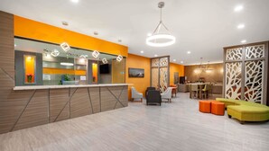 A modern reception area with a counter, seating, and a decorative partition. - Baymont by Wyndham Houston Hobby Airport (Houston)