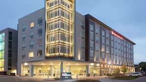 A modern hotel with a prominent corner tower, large windows, and a well-lit entrance.
