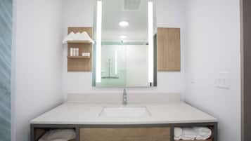 A modern bathroom with a large mirror, a white sink, and built-in towel storage.