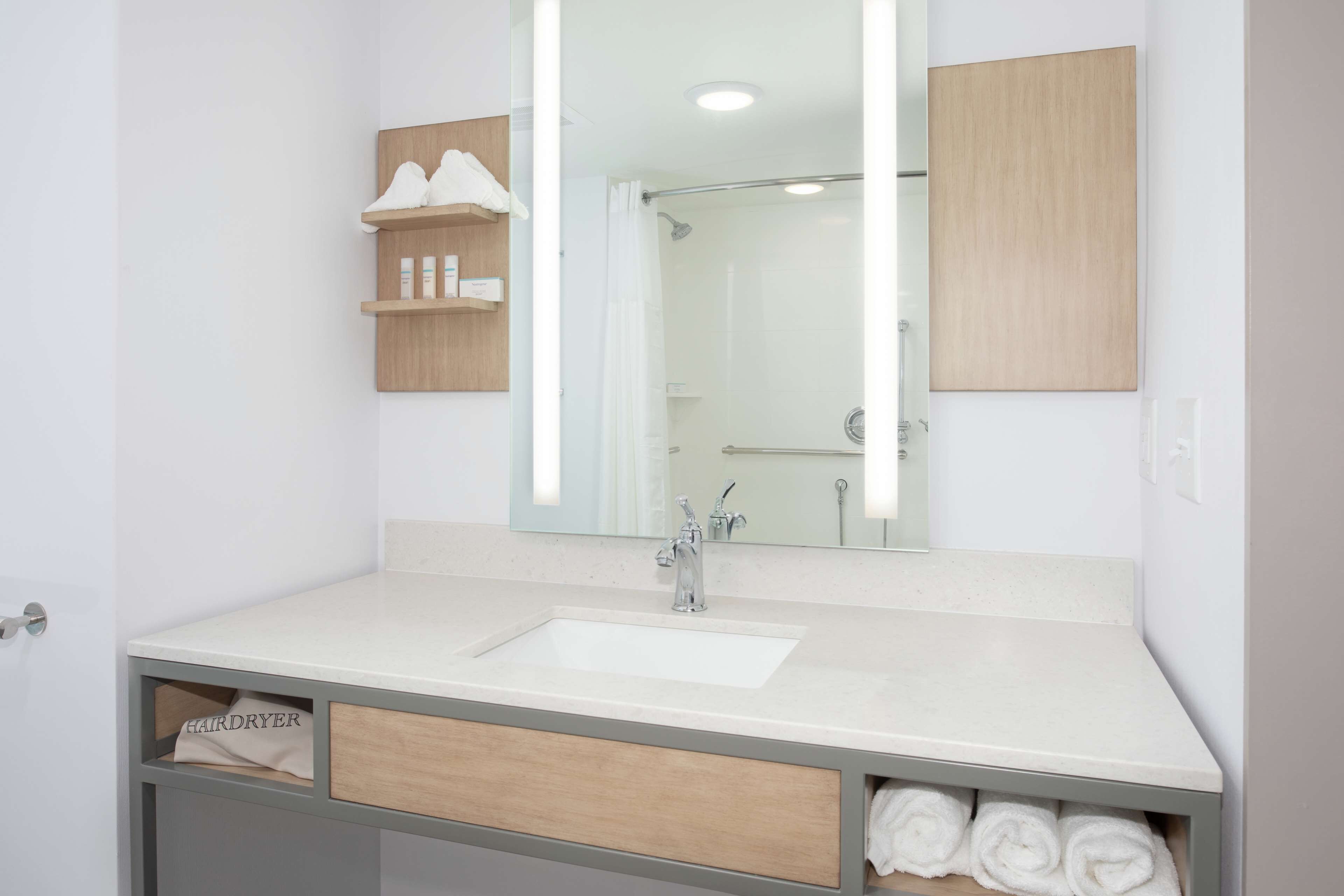 Une salle de bain avec un lavabo blanc, un miroir et un espace douche.