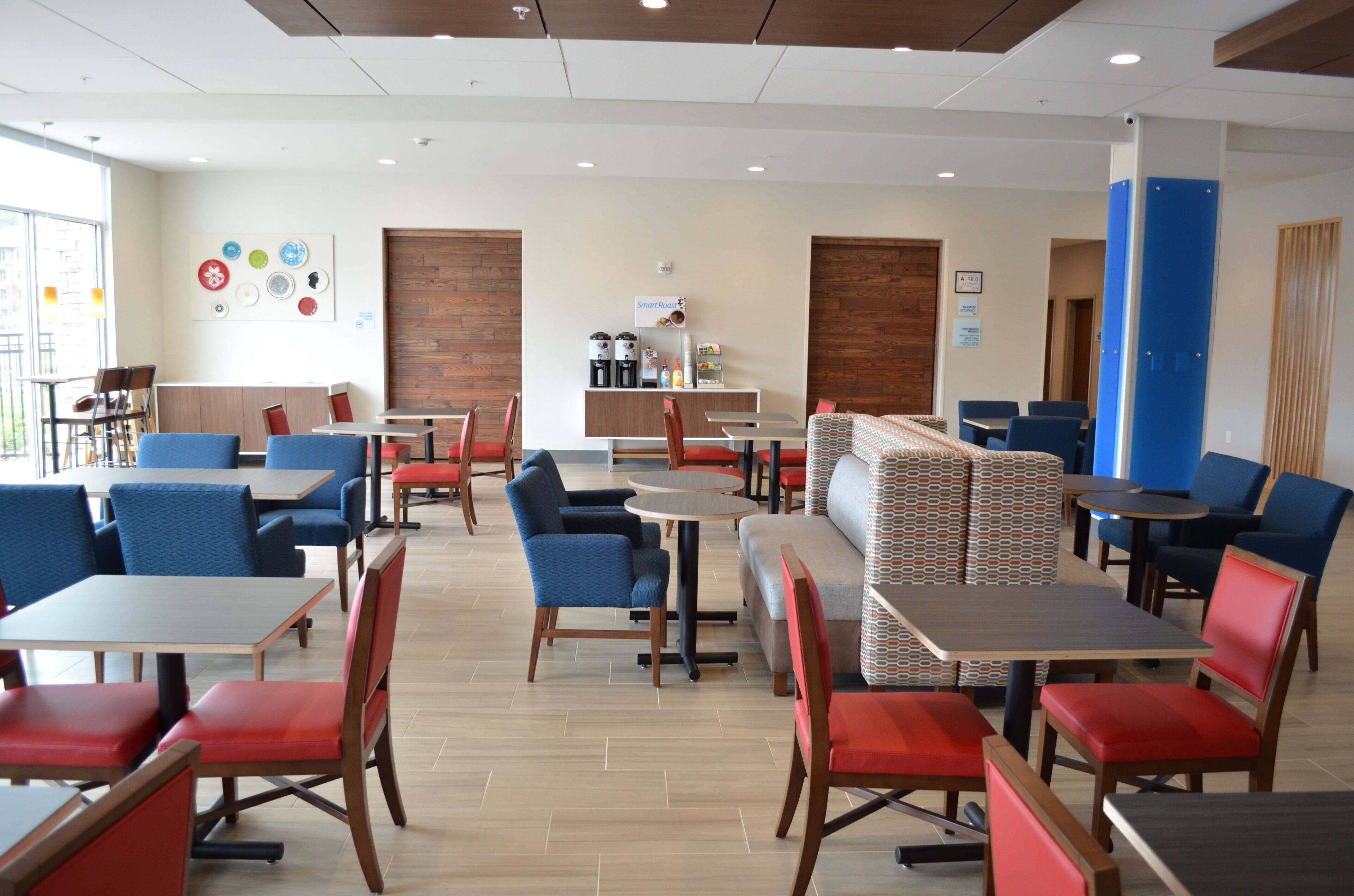 Un restaurante moderno con varias zonas de estar, incluyendo mesas y cabinas, y una estación de café.