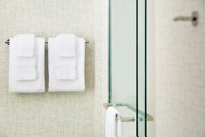A bathroom with a geometric patterned wall, a glass shower enclosure, and two white towels hanging on a towel rack. - Holiday Inn Express & Suites Raleigh Airport - Brier Creek by IHG (Raleigh)