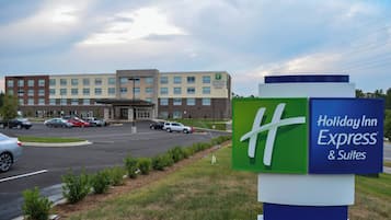 A Holiday Inn Express & Suites hotel with a parking lot and a large building in the background.
