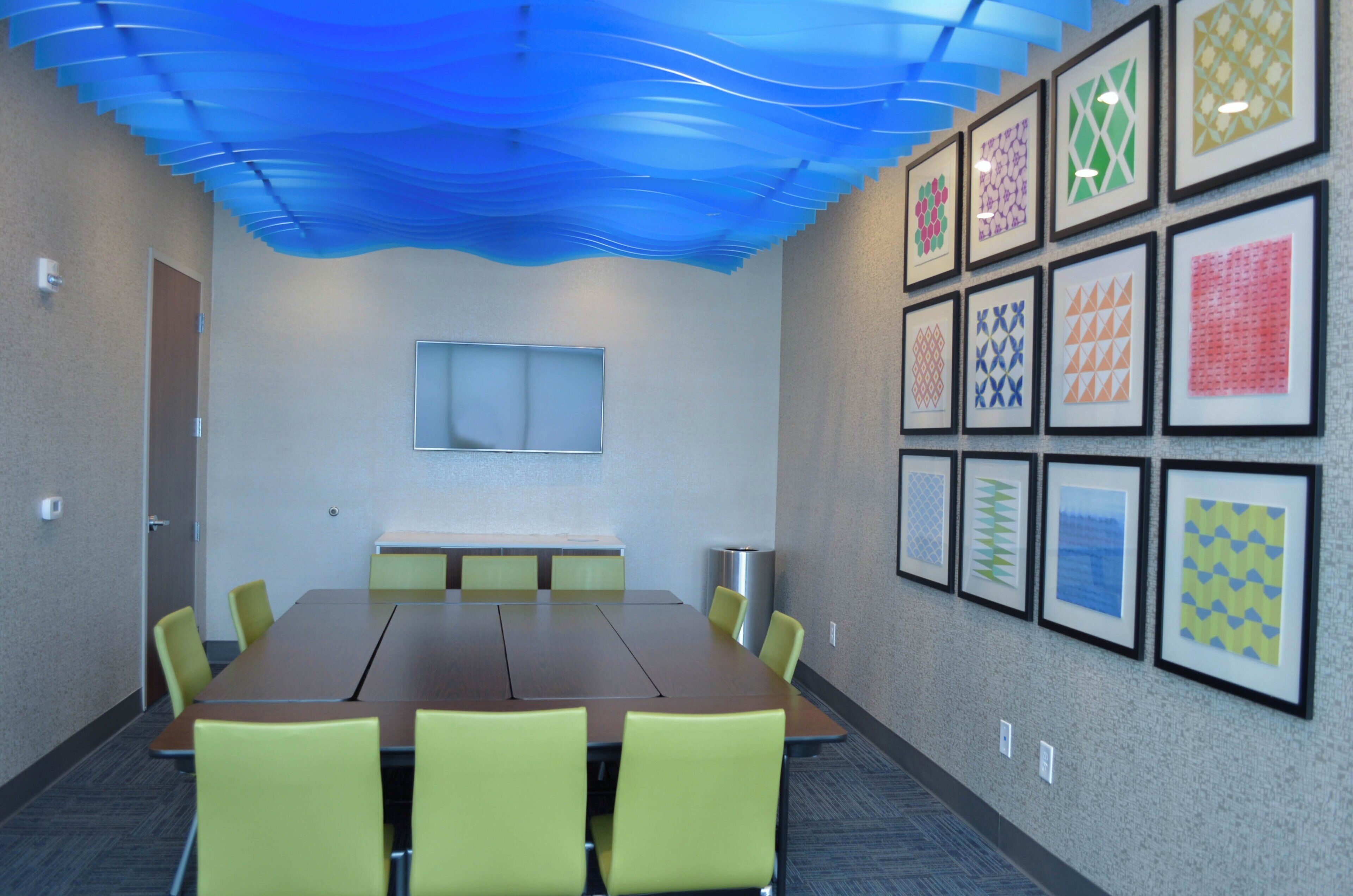Uma sala de conferências com uma mesa comprida, cadeiras, um quadro branco e quadros nas paredes.
