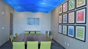 Uma sala de conferências com uma mesa comprida, cadeiras, um quadro branco e quadros nas paredes.