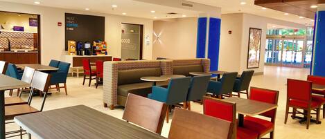 A modern cafe interior with seating arrangements, a coffee station, and a wall with a 'Good Morning' sign.
