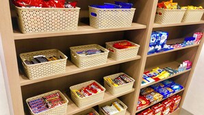 A shelf stocked with various snack items, including boxed cereals and candy.