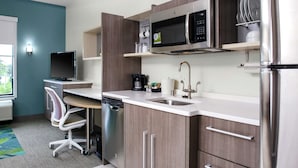 A modern kitchen with a dishwasher, microwave, and stainless steel refrigerator. - Home2 Suites by Hilton Fort Collins (Fort Collins)