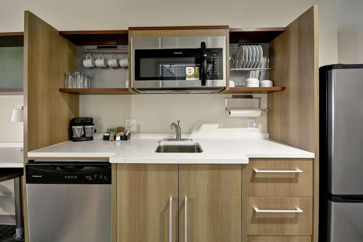 Una cocina compacta con microondas integrado, lavavajillas y refrigerador.