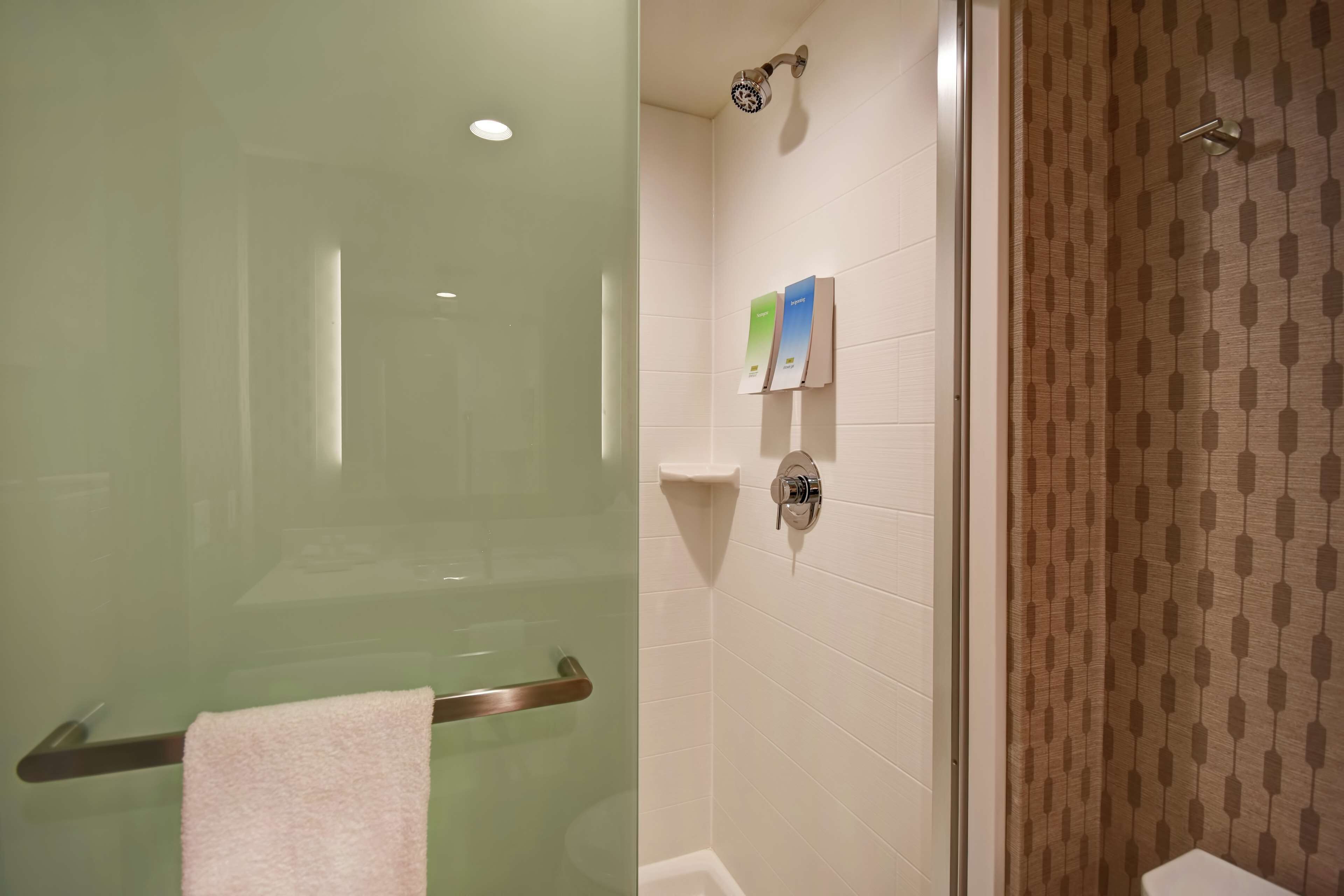 A bathroom with a glass shower enclosure, a towel rack, and a showerhead.