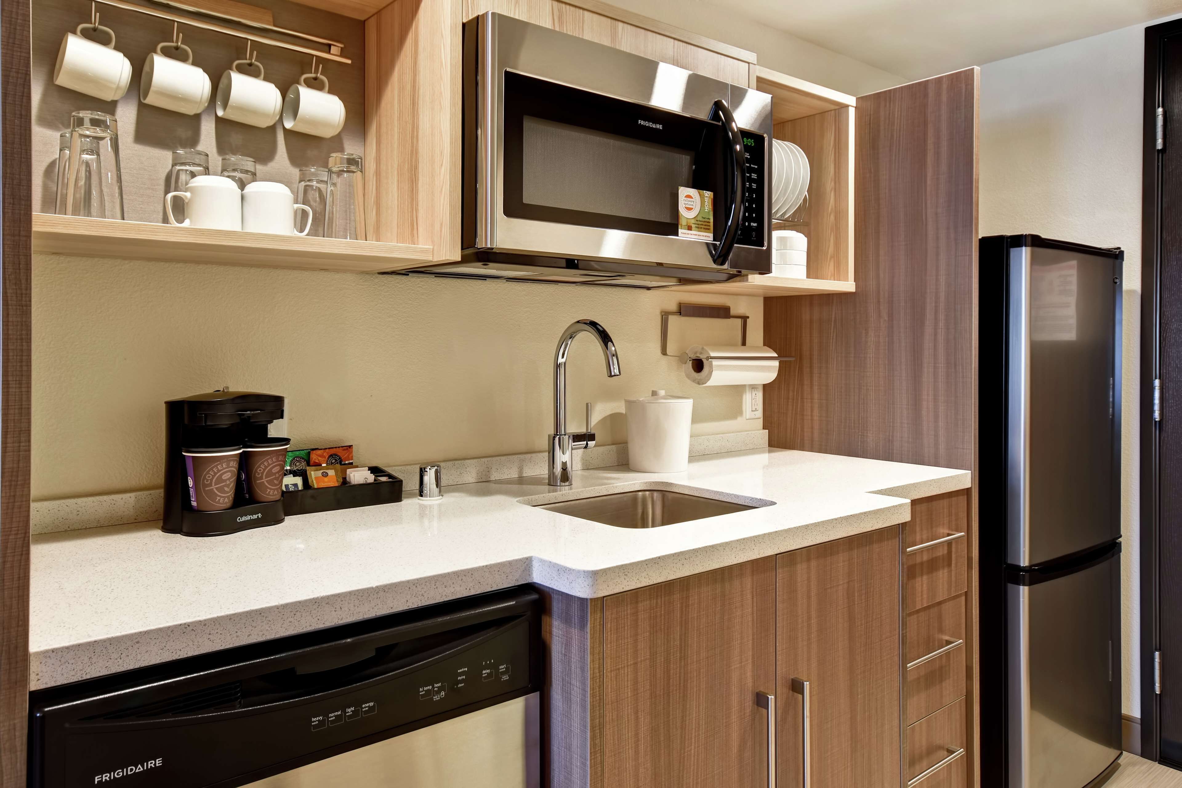 A modern kitchen with a stainless steel microwave, a coffee maker, and a dishwasher.