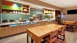 Un restaurante moderno con mesas y sillas de madera, una barra con productos alimenticios y un televisor montado en la pared.