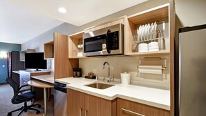 Una cocina moderna con armarios de madera, un refrigerador de acero inoxidable, un microondas y un lavamanos.
