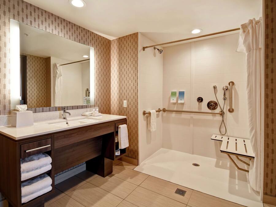 Un baño moderno con lavamanos doble, ducha a ras de suelo y un espejo grande.