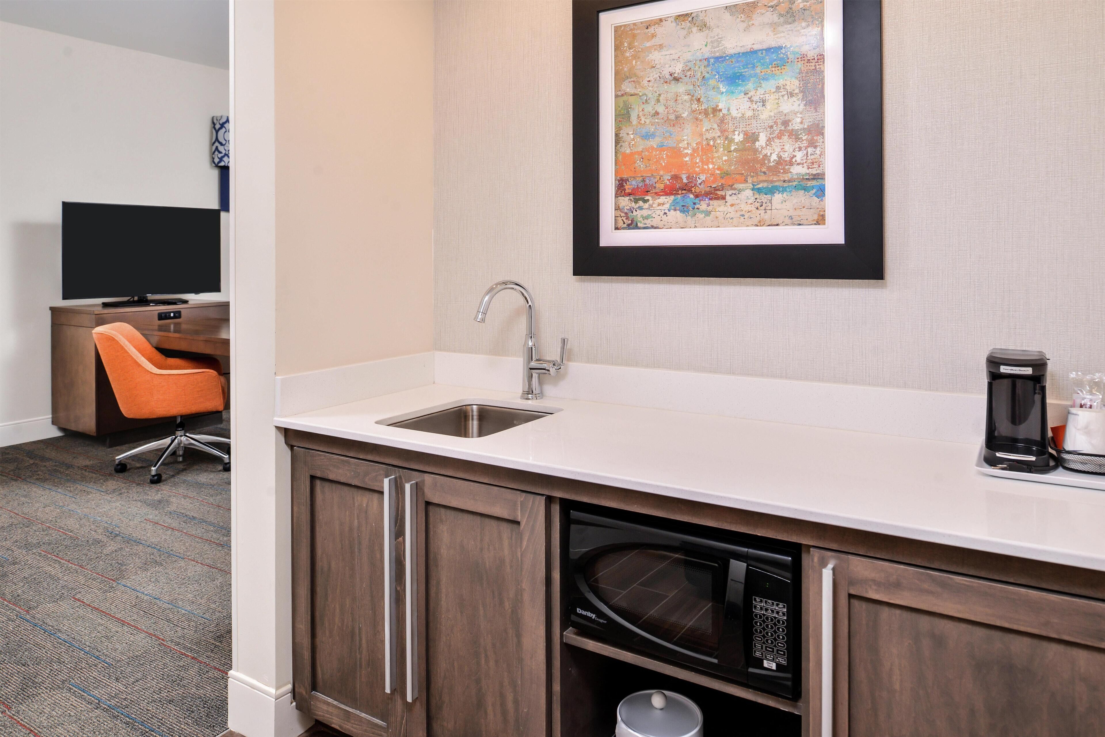 A modern kitchen with a built-in microwave, a sink, and a coffee maker.