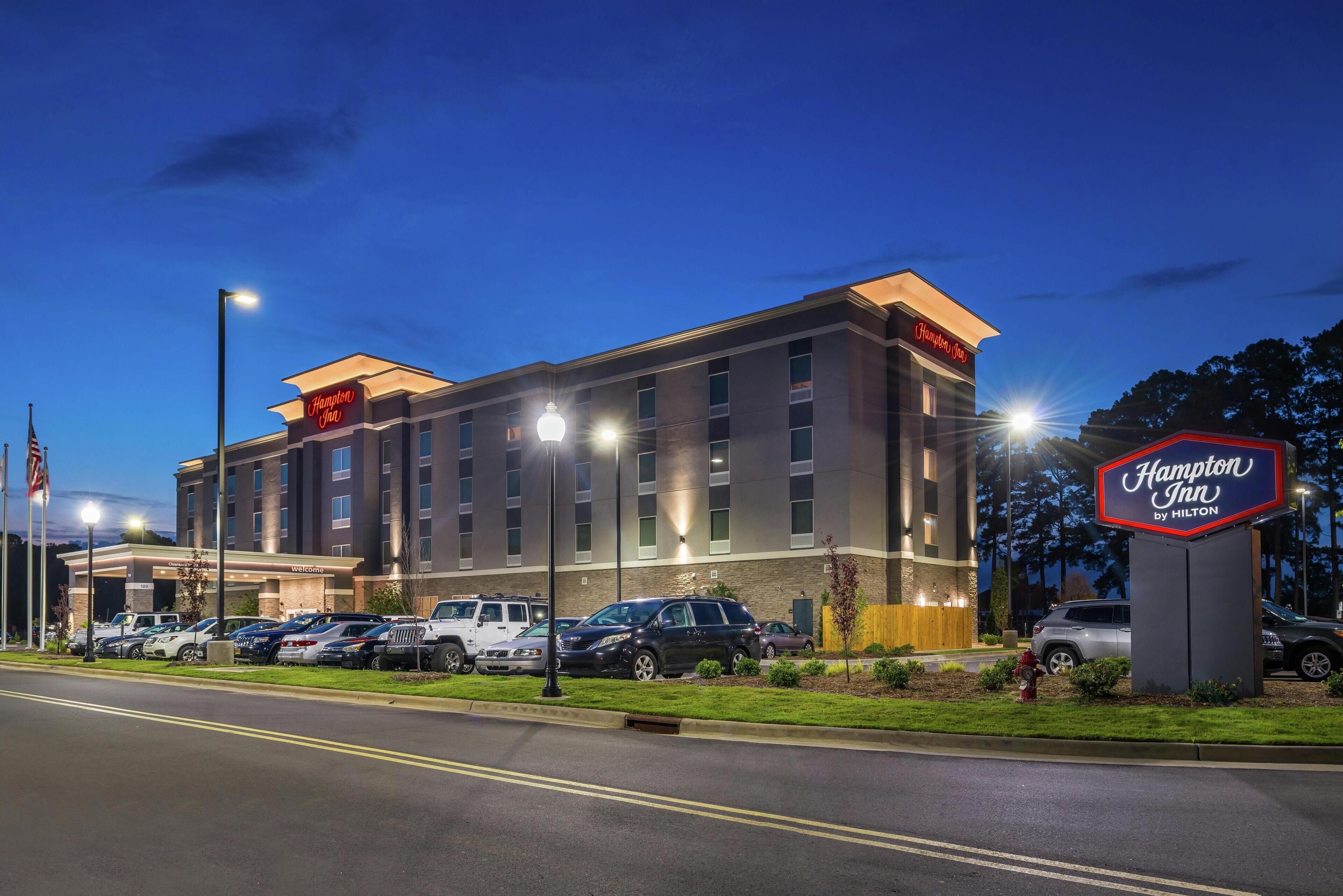 Un hôtel Hampton Inn by Hilton doté d’un parking et d’une entrée bien éclairée.