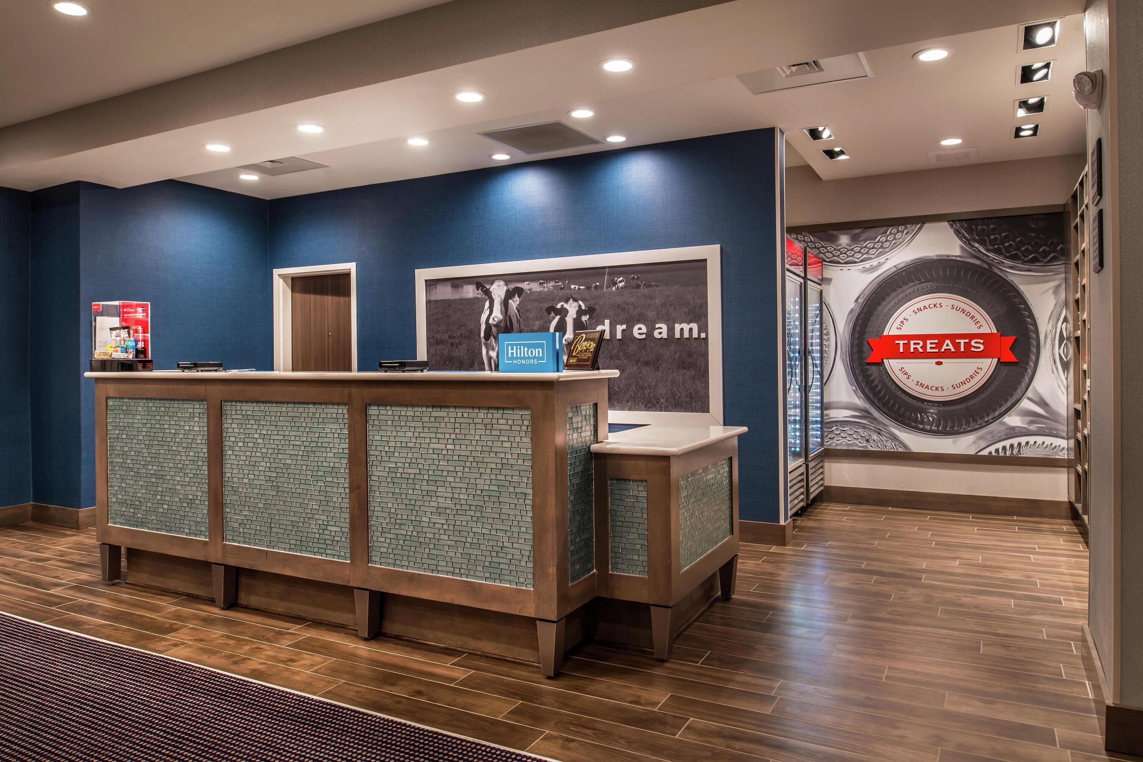 A reception area with a blue wall, a framed picture, a counter with a sign, and a wall with a circular design and text.
