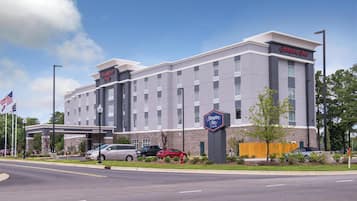 A Hampton Inn hotel with a modern design, featuring a large parking lot and a welcoming entrance.