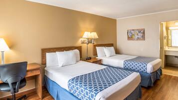 A hotel room with two beds, a desk, a chair, and a nightstand with lamps.