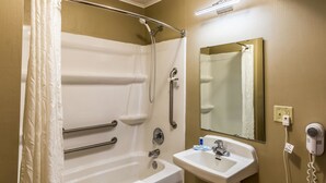 Un baño con bañera, secador de manos, lavabo y espejo.