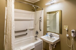Un baño con bañera, secador de manos, lavabo y espejo.