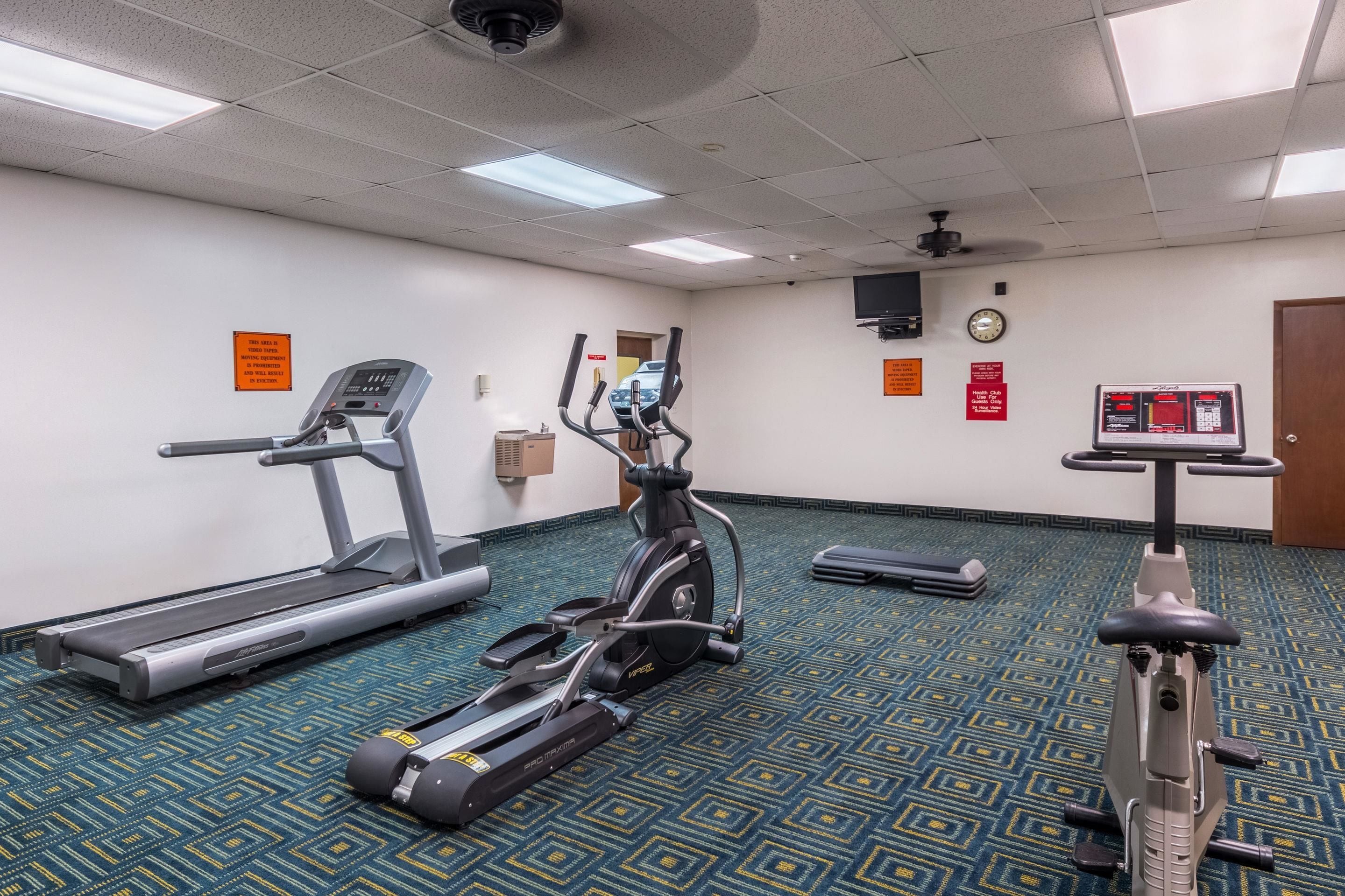 A fitness room with treadmills, an elliptical, and a stationary bike.