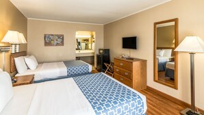 Una habitación de hotel con dos camas, un escritorio, un aparador, un televisor y un espejo.