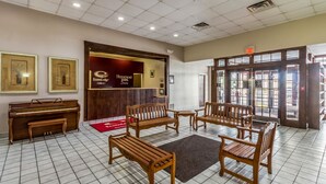 Un vestíbulo con un piano, bancos de madera y una recepción para Rodeway Inn.