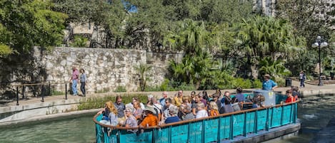 Une excursion en bateau avec des passagers, entourés de verdure et d’un mur de pierre.