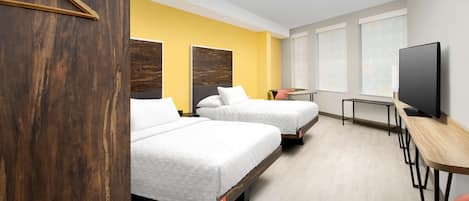 Habitación de hotel con dos camas, televisor y escritorio.
