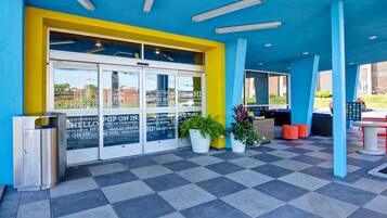 Un edificio de colores vivos con fachada azul y amarilla, grandes puertas de vidrio y suelo a cuadros.