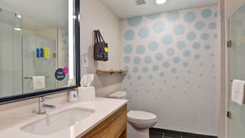 A modern bathroom with a large mirror, a sink, a toilet, and a shower area.