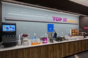 Mostrador de desayuno con un cartel que dice "TOP IT BREAKFAST" y una barca de gofres.
