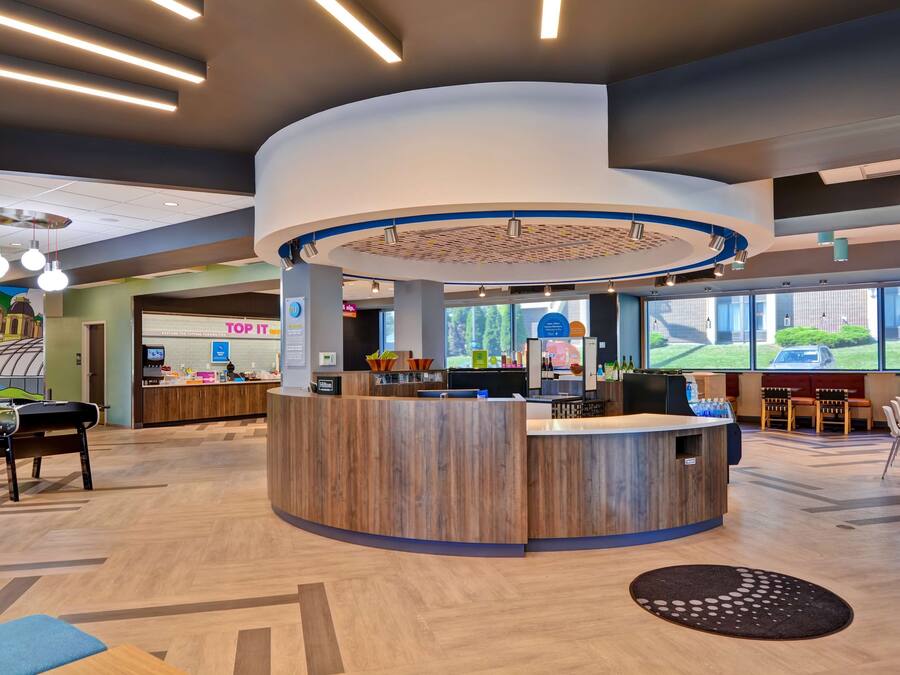 A modern reception area with a central desk, seating area, and large windows offering views of the outdoors.