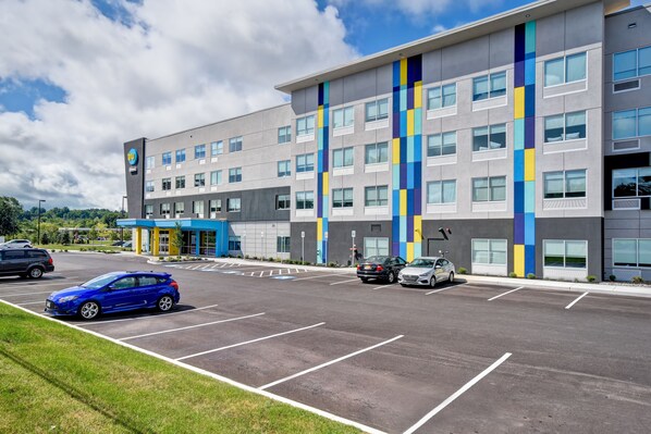 A modern hotel with a parking lot and a blue car parked in one of the spaces.