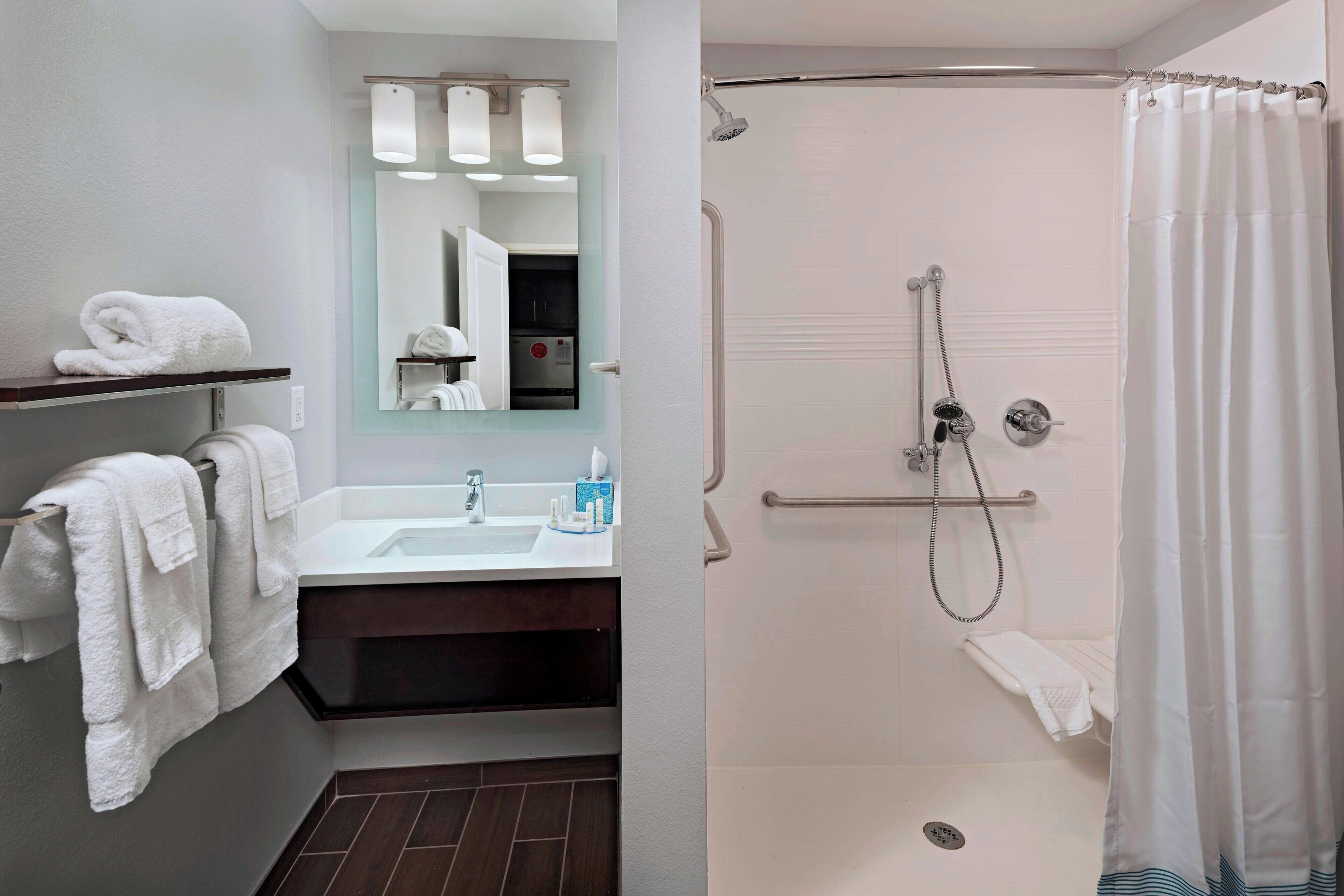 Un baño moderno con ducha, lavamanos y espejo.