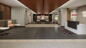 Um lobby moderno com área de estar central, balcão de recepção e piso estampado.
