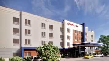 A Hampton Inn hotel with a modern facade, multiple windows, and a gas station entrance.