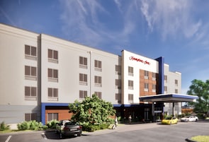 A Hampton Inn hotel with a modern facade, multiple windows, and a gas station entrance.
