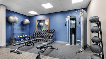 Un gimnasio con equipamiento de ejercicio, incluyendo una banca, mancuernas y una estructura para sentadillas.