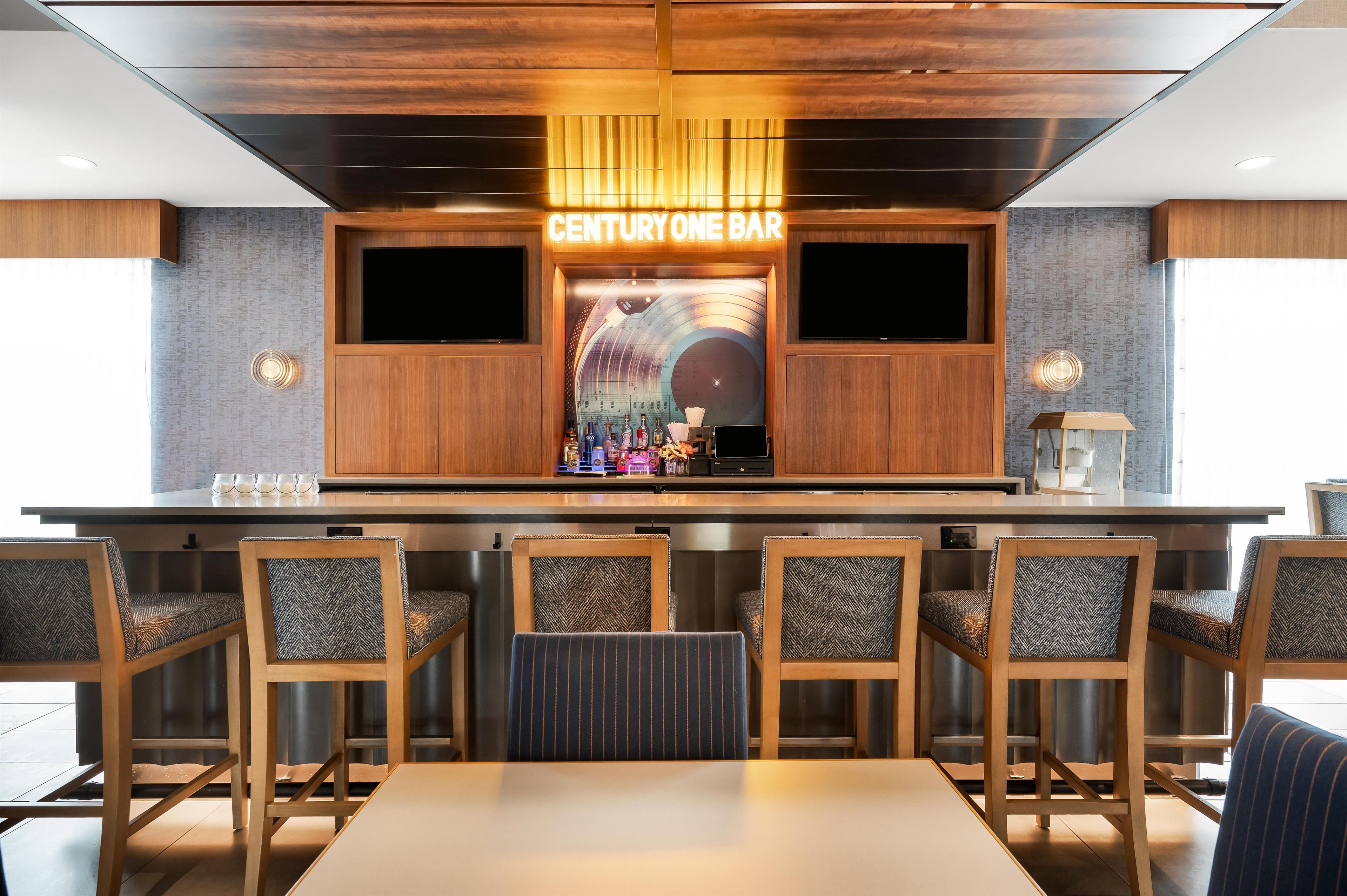 A bar area with wooden furniture and a neon sign reading 'CENTURY ONE BAR'.
