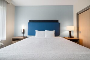 A hotel room with a large bed, two bedside tables, a nightstand, a lamp, and a wall-mounted phone. - Hampton Inn Nashville Airport Century Place, TN (Nashville)