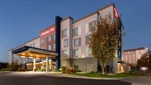 Um hotel Hampton Inn com entrada desobstruída, fachada bem iluminada e placa convidativa.