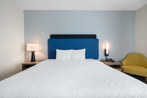 A hotel room with a bed, two bedside tables, a lamp, a phone, and a chair. - Hampton Inn Nashville Airport Century Place, TN (Nashville)
