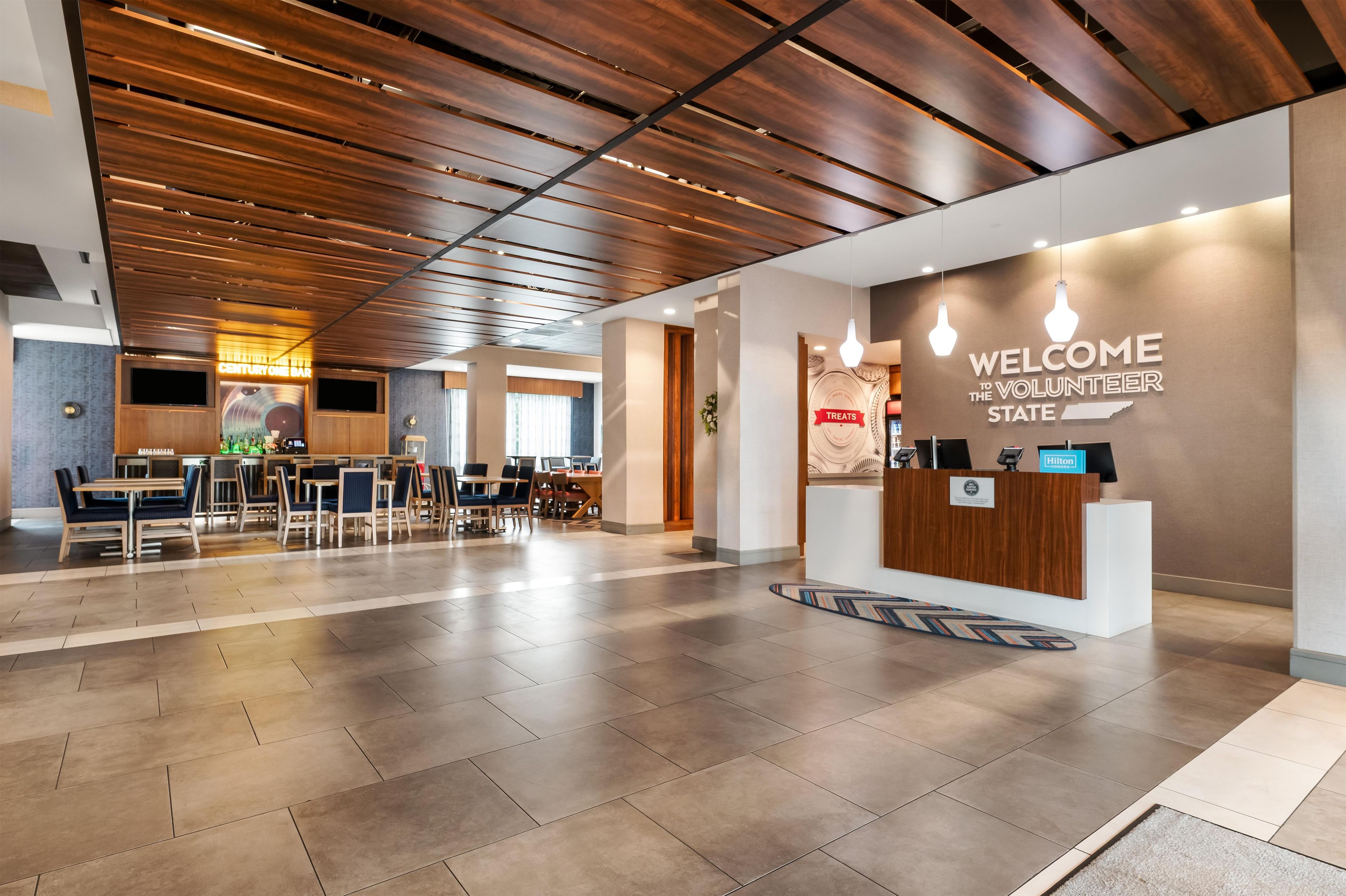 Een moderne lobby met een houten plafond, een receptiebalie en een bar.