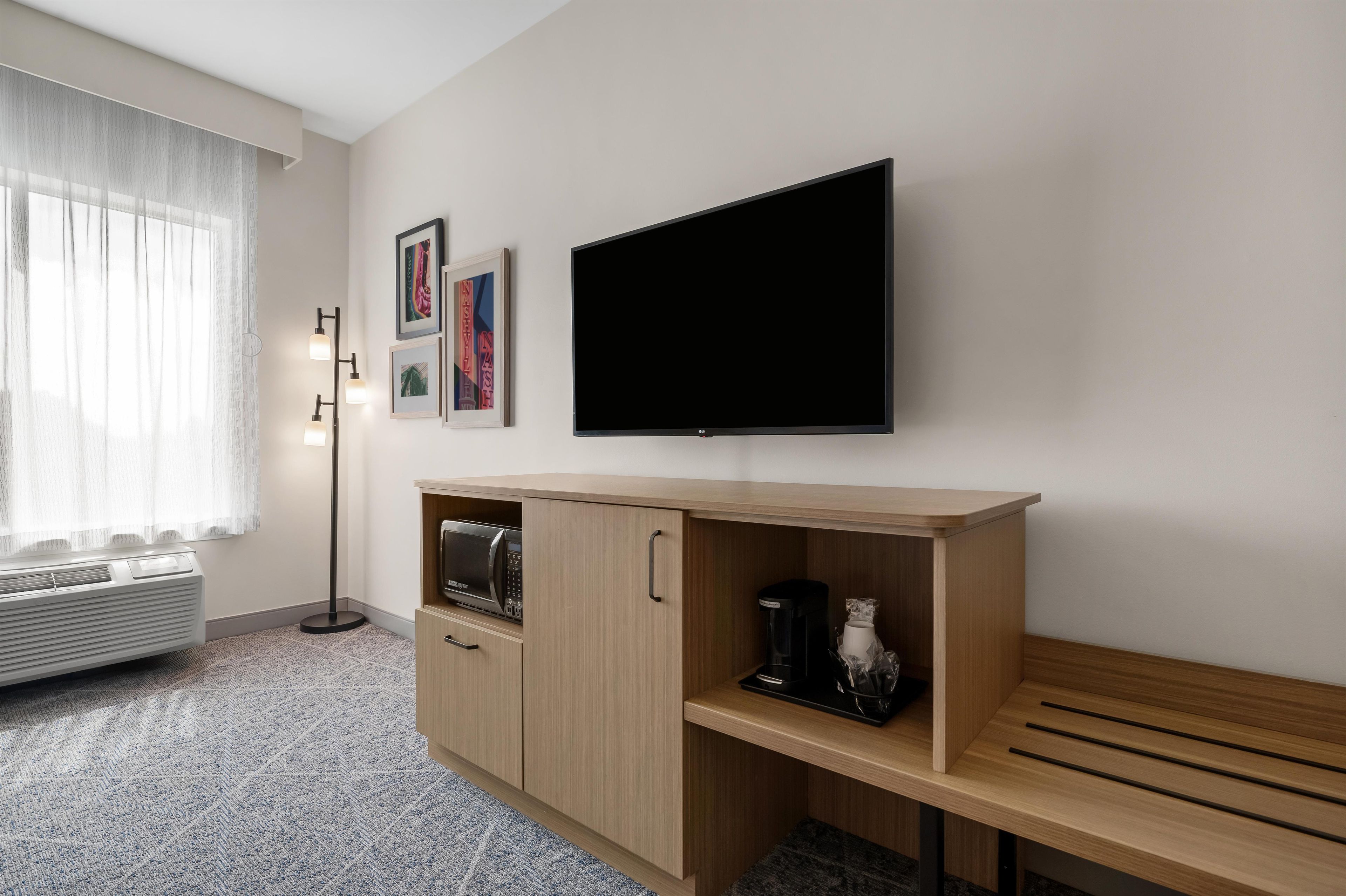 Quarto de hotel com televisão de tela plana, minibar, micro-ondas e cafeteira.