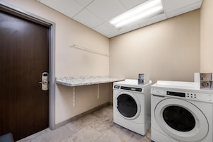 Un cuarto de lavandería con una puerta, una encimera y dos lavadoras.