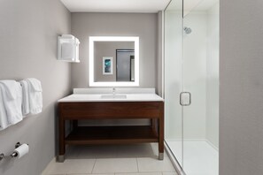 A modern bathroom with a wooden vanity, a mirror with integrated lighting, a shower, and a toilet. - Hampton Inn Nashville Airport Century Place, TN (Nashville)